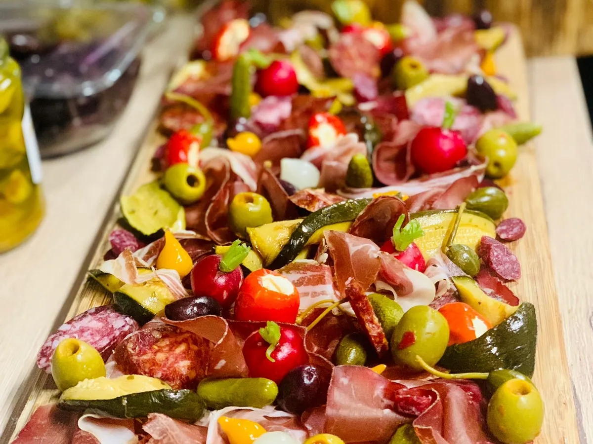 A long sharing board of charcuterie and vegetables